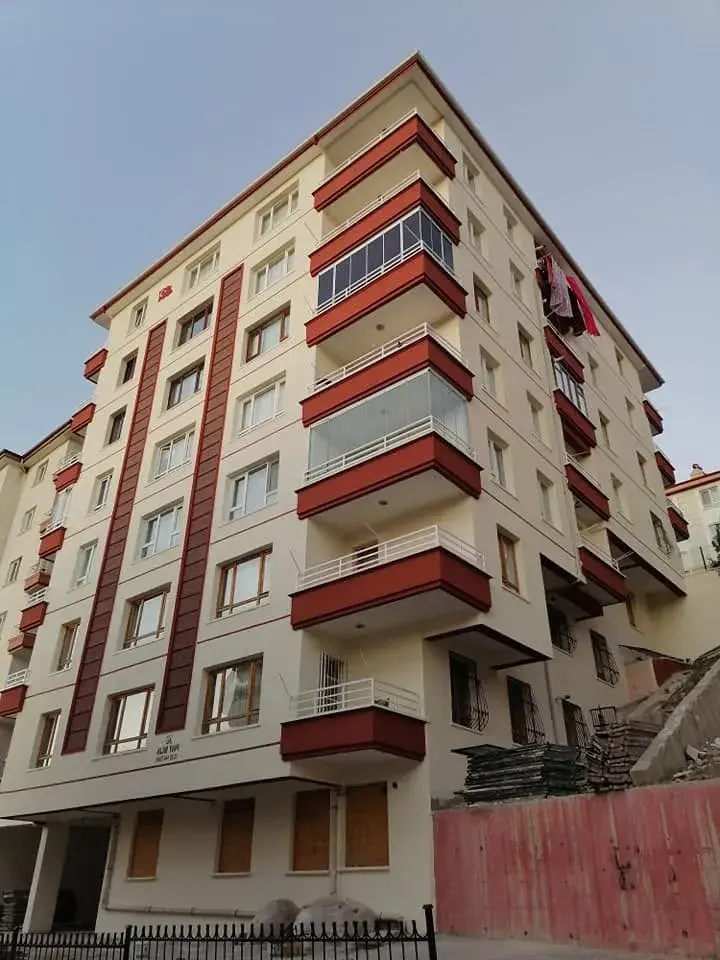 Keçiören Esertepe'de yedi-sekiz katlı köşe bina, krem cephe ve kırmızı-kahve balkon alınları