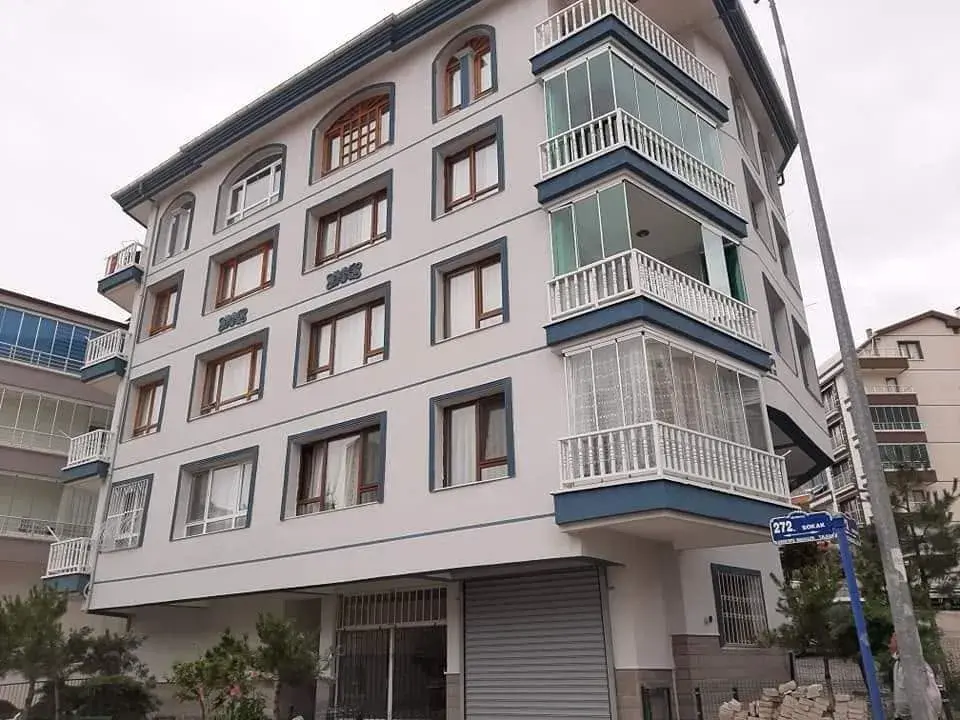 Keçiören İncirli'de beş katlı köşe bina, beyaz cephe, lacivert silmeler ve kemerli pencereler
